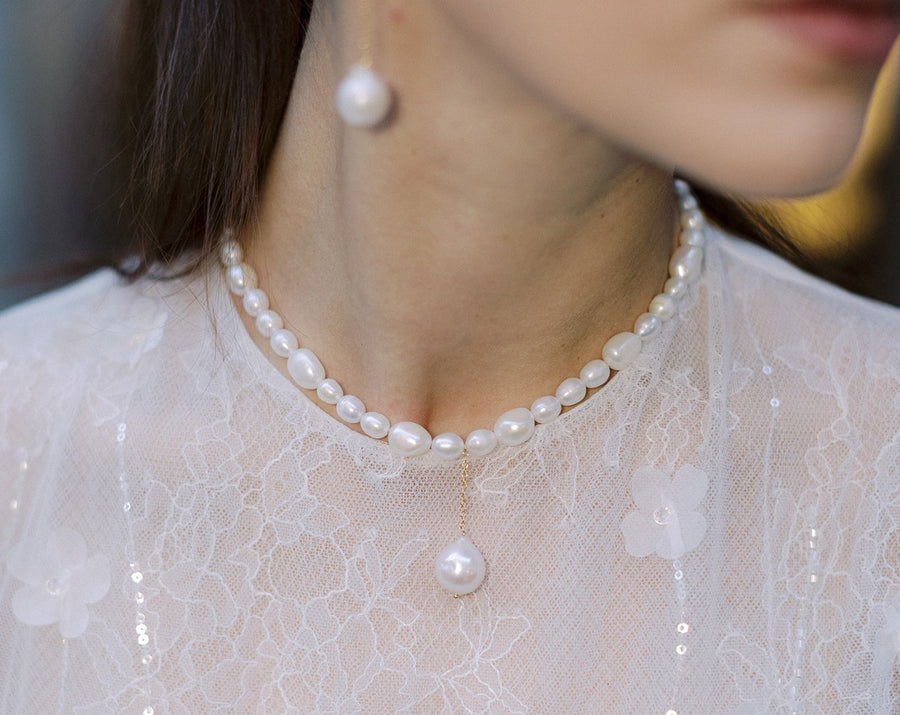 Bride wearing pearl necklace with large pearl drop.