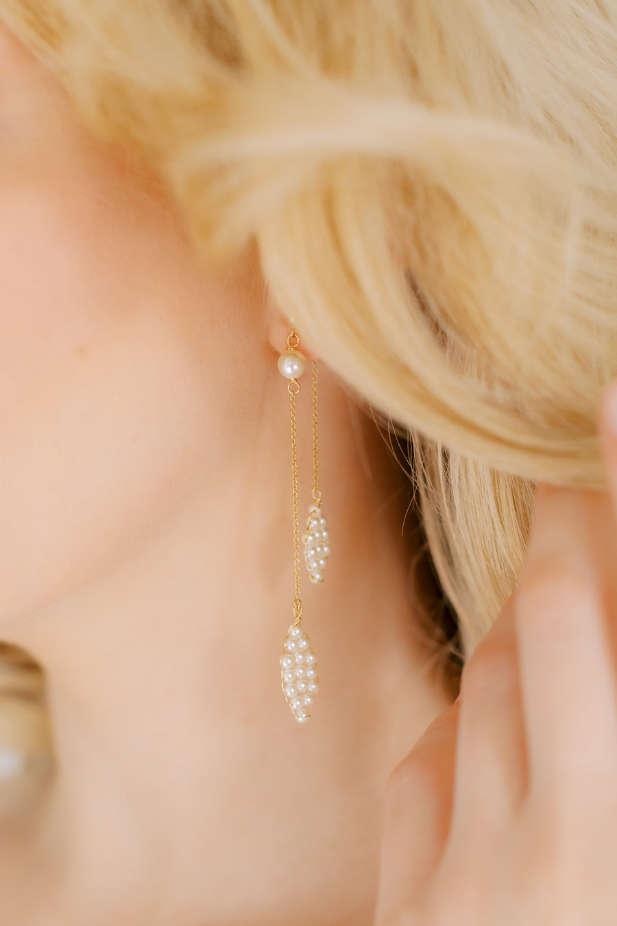 Close up of bride wearing long pearl petal bridal earrings.