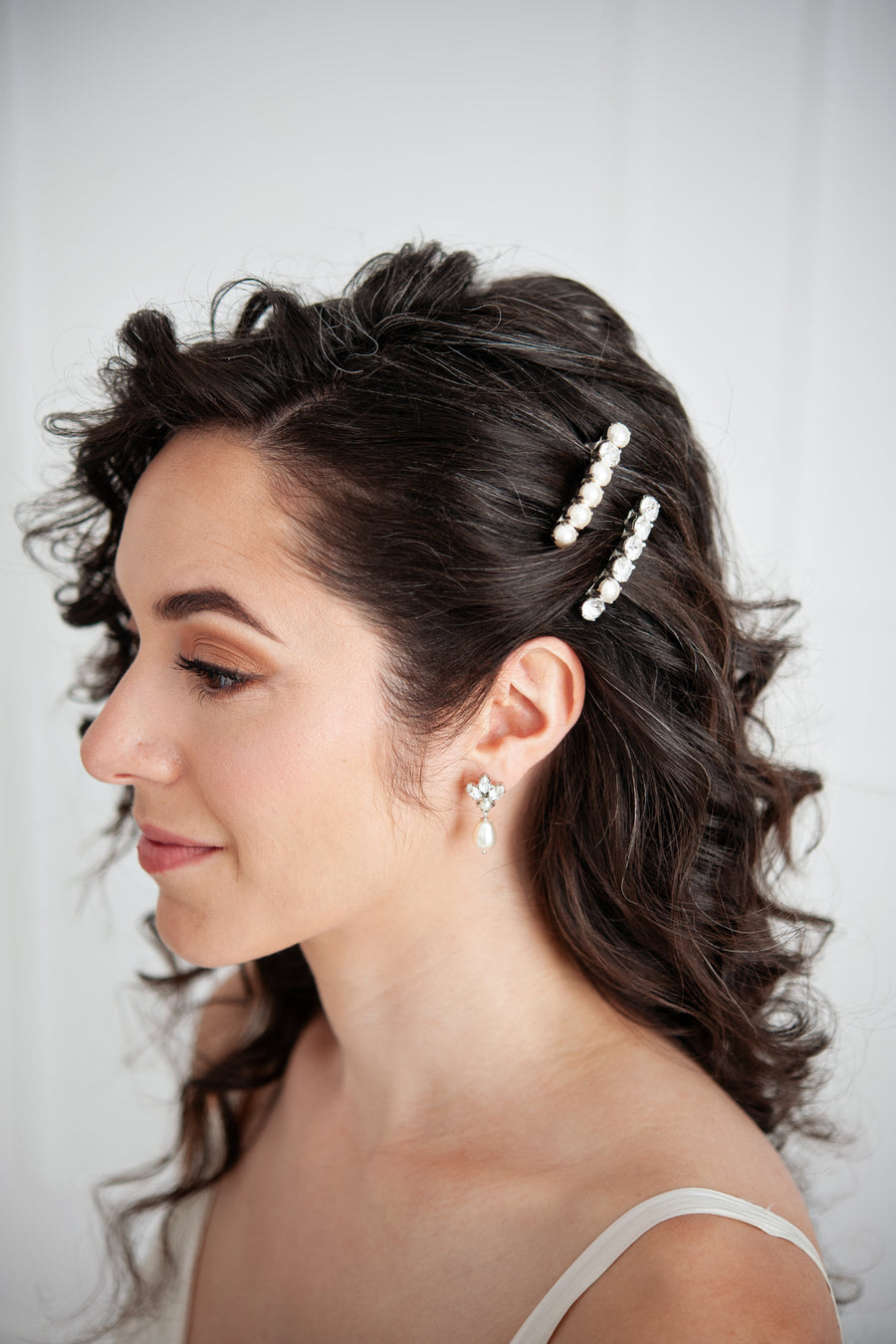 Bride wearing matching pearl wedding set of pearl earrings and crystal and pearl barrettes.