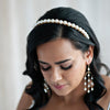 Bride with hair worn down wearing a pearl headband and matching pearl chandelier earrings by Joanna Bisley Designs.