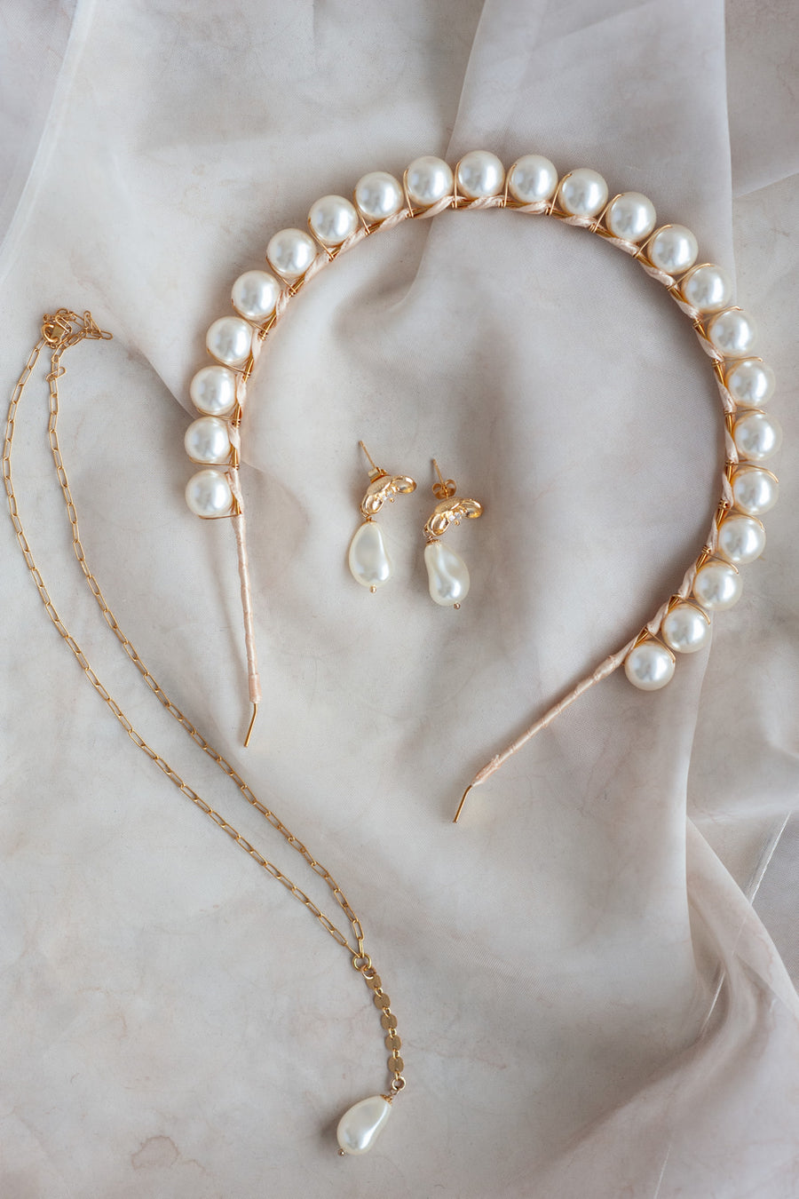 Matching pearl bridal accessories including a pearl headband, pearl wedding earrings and necklace.